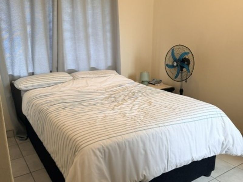A simple bedroom featuring tiled flooring and neutral wall finishes, providing a functional and clean space.