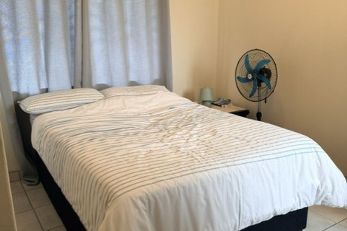 A simple bedroom featuring tiled flooring and neutral wall finishes, providing a functional and clean space.