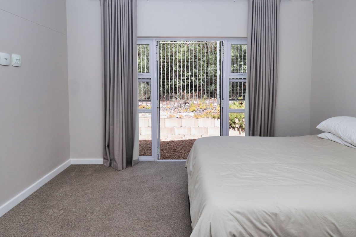 A well-maintained bedroom featuring neutral carpeting, neutral wall tones, and a sliding glass door providing direct access to the rear garden area.