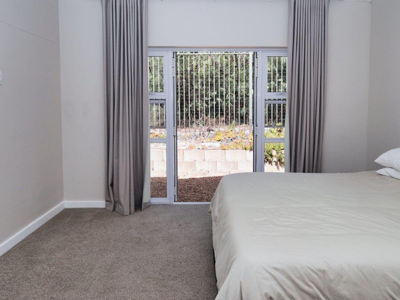 A well-maintained bedroom featuring neutral carpeting, neutral wall tones, and a sliding glass door providing direct access to the rear garden area.