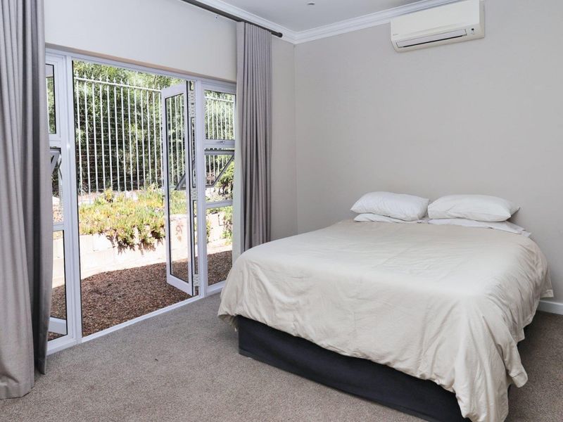 A well-maintained bedroom featuring neutral carpeting, a split-system air conditioner, and direct access to the exterior through a sliding glass door.