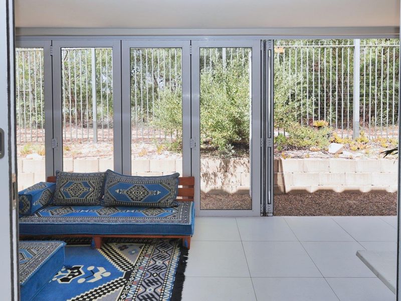 A bright, enclosed patio area featuring large bi-fold glass doors that open onto a landscaped rear garden with a retaining wall.
