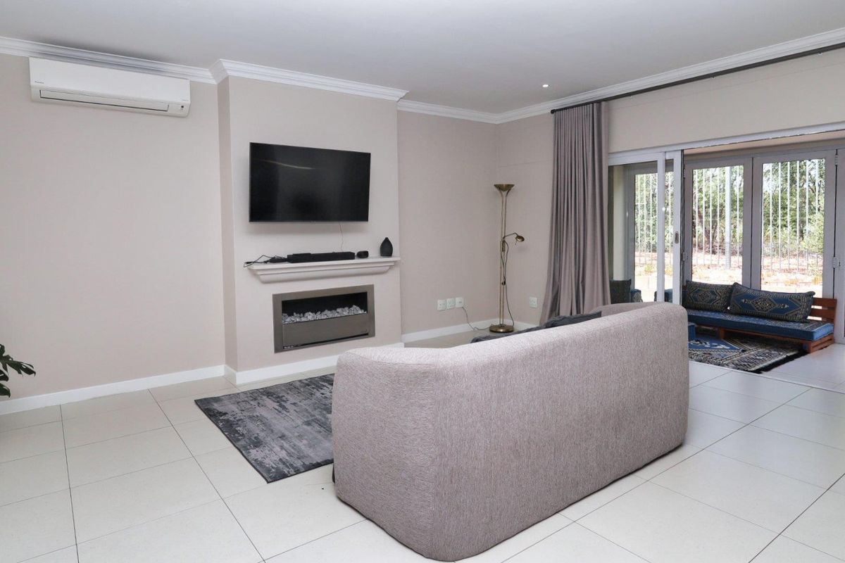 A well-maintained living room featuring tiled floors, a built-in fireplace, and large sliding glass doors that provide access to the outdoor patio area.