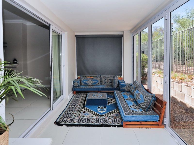 A bright, enclosed patio area featuring large sliding glass doors, tiled flooring, and roller blinds, offering a seamless transition to the outdoor space.