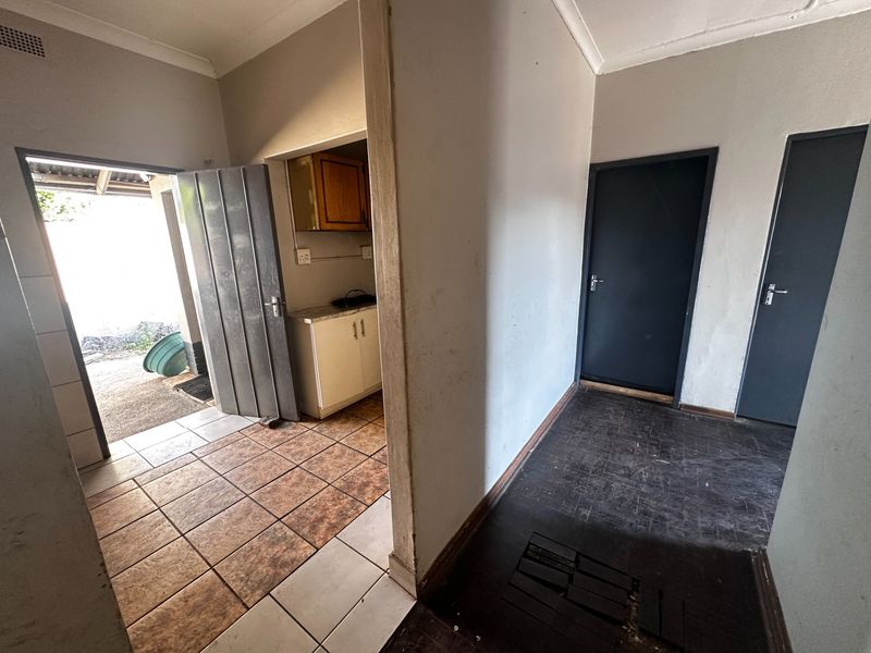 A functional hallway area featuring tiled flooring, built-in cabinetry, and access to multiple rooms, presenting a blank canvas for renovation.