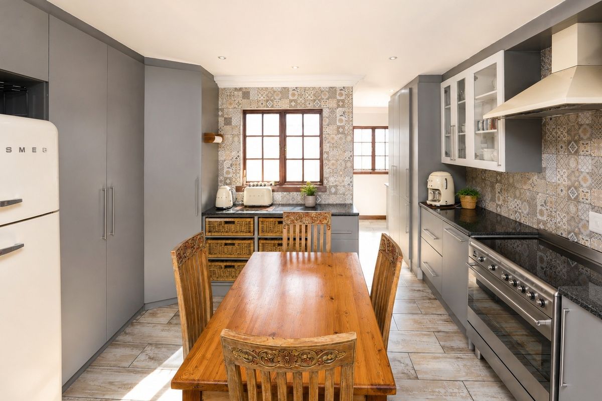 Modern kitchen featuring grey cabinetry, granite countertops, decorative tiled backsplash, and a built-in stove with extractor fan, offering a functional and stylish cooking space.