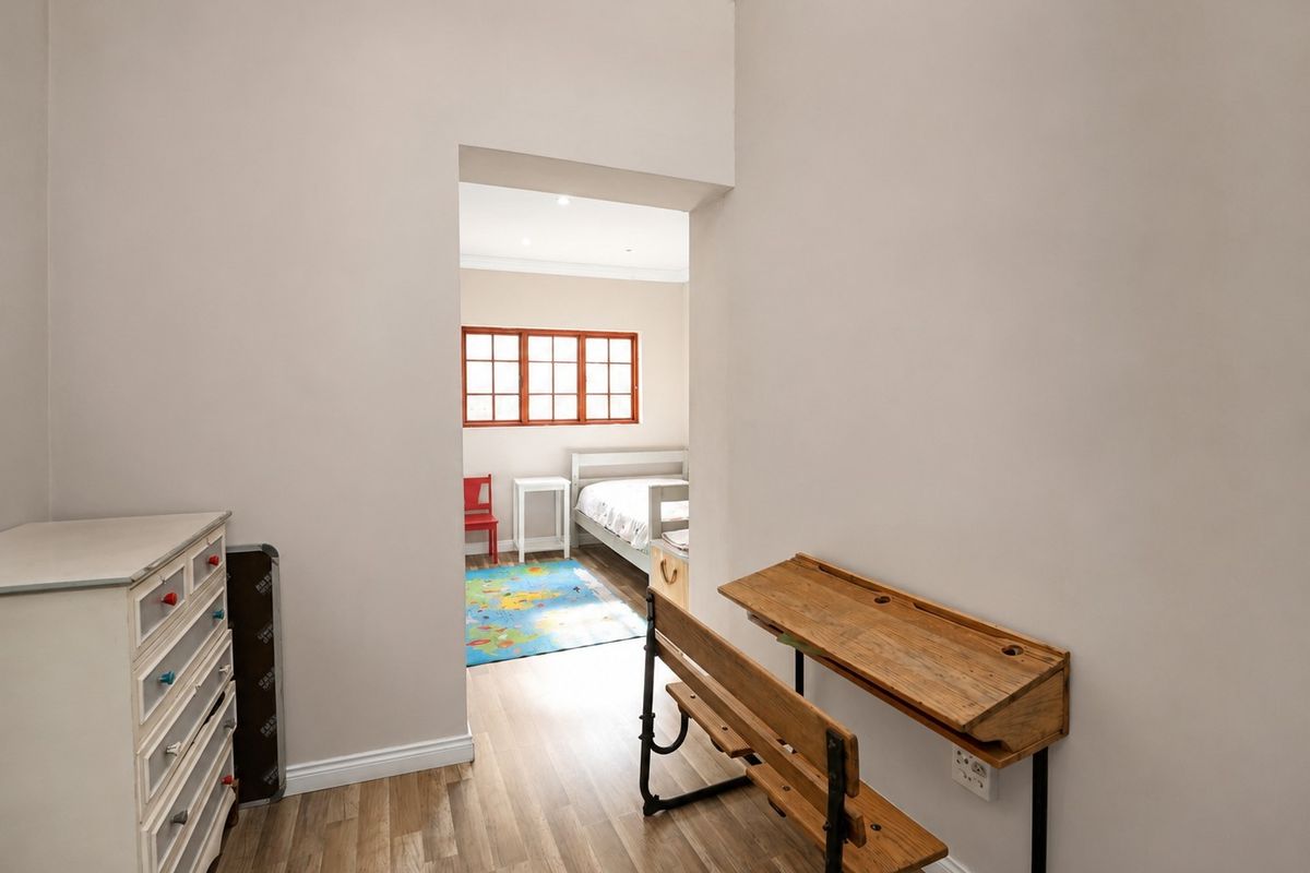 A view through a doorway into a bedroom featuring laminate flooring, neutral wall finishes, and classic coving detail.