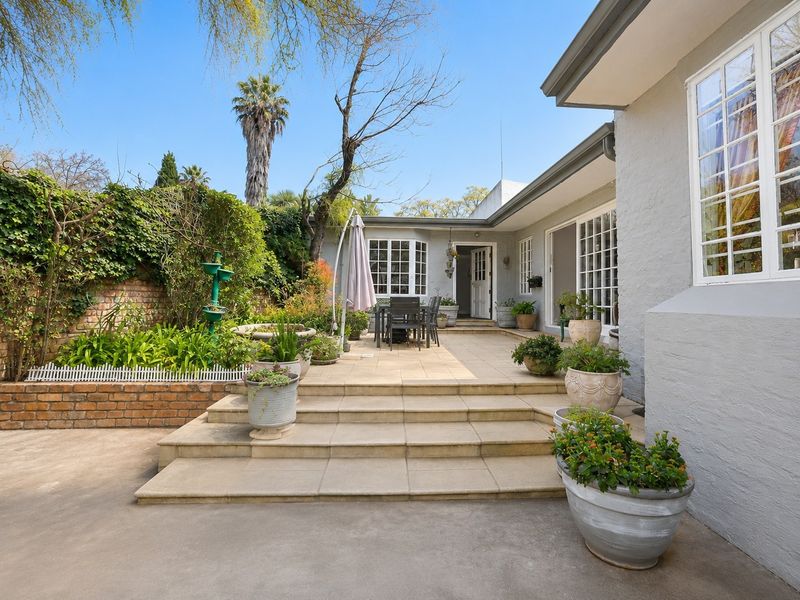 A well-maintained rear patio area featuring tiled steps, brick retaining walls, and direct access to the home through classic multi-pane windows and doors.