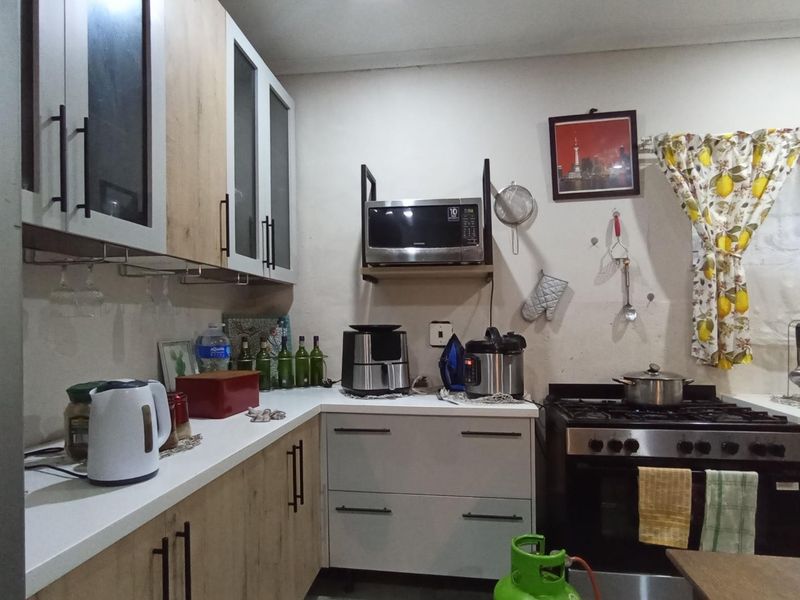 A functional kitchen featuring two-tone cabinetry, a gas stove with oven, and wall-mounted shelving for a microwave.