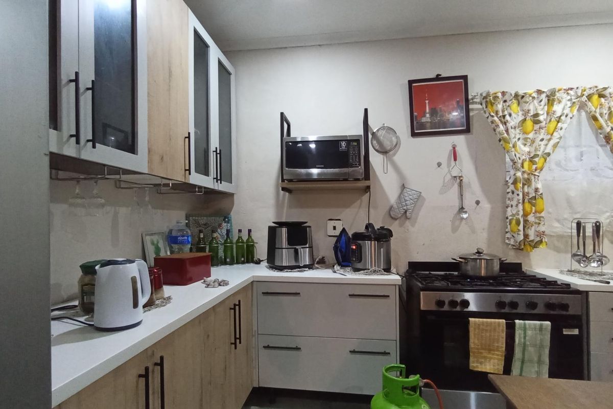 A functional kitchen featuring two-tone cabinetry, a gas stove with oven, and wall-mounted shelving for a microwave.