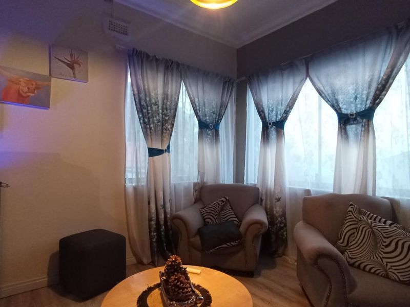 A cozy living room area featuring laminate flooring and corner windows with natural light.