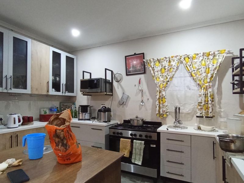 A functional kitchen featuring built-in cabinetry, a gas stove with extractor, and a double sink setup with ample counter space.
