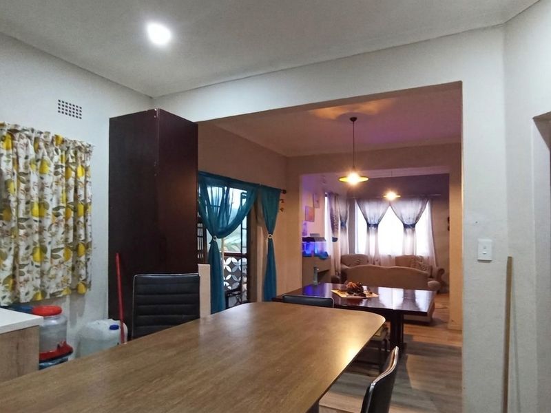 Open-plan living and dining area featuring laminate flooring, neutral walls, and integrated cabinetry, creating a functional and connected living space.