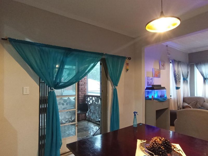 Open plan living and dining area featuring pendant lighting and direct access to an outdoor patio through a sliding security gate.