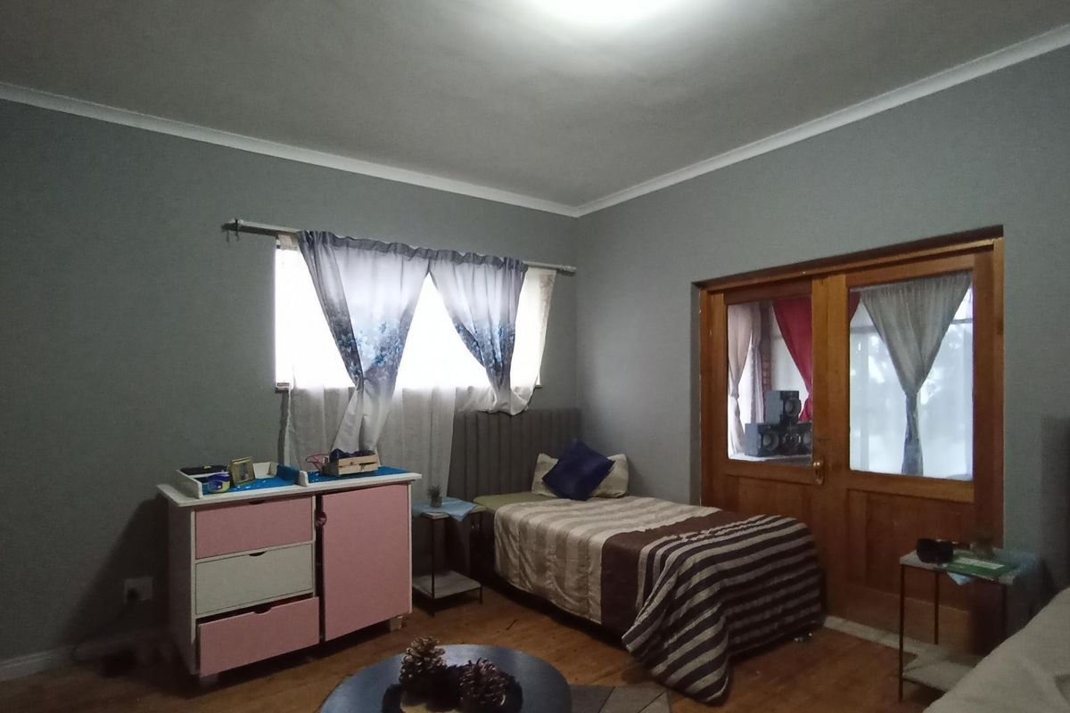 A bedroom featuring laminate flooring, built-in wardrobe storage, and a wooden door leading to an adjacent space.
