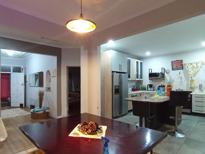 Open-plan living and kitchen area featuring modern cabinetry, a central kitchen island, and tiled flooring, creating a functional and connected home layout.