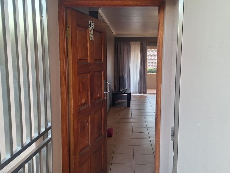 View through the main entrance door into the apartment, featuring tiled flooring and a security gate at the threshold.