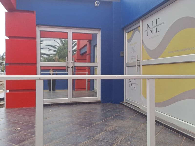 Front entrance of the office building featuring tiled landing, aluminium glass doors, and branded window decals.