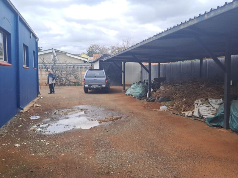 Rear exterior area of the office property featuring a large metal carport structure and unpaved ground surface.