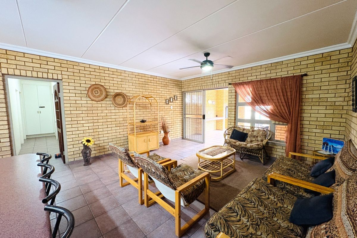 Spacious living area featuring exposed brick walls, tiled flooring, a ceiling fan, and direct access to an outdoor patio through sliding glass doors.