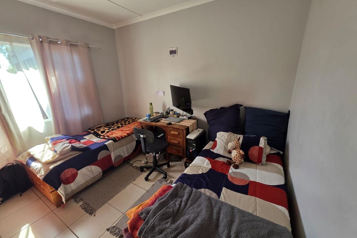 A functional bedroom featuring tiled flooring and natural light from a window, suitable for a guest room or child's bedroom.