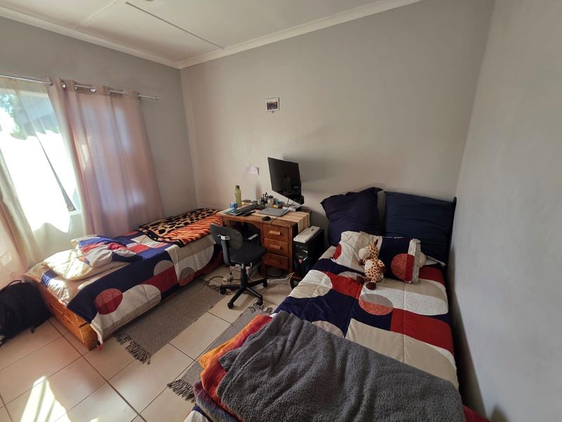A functional bedroom featuring tiled flooring and natural light from a window, suitable for a guest room or child's bedroom.