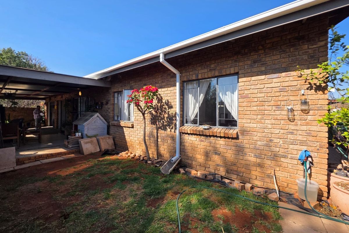 Rear view of the house featuring a face brick facade, covered patio area, and established garden space.