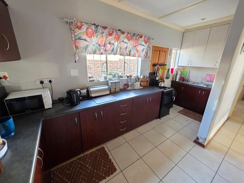 Functional kitchen featuring dark wood-look cabinetry, contrasting countertops, ceramic tiled flooring, and a freestanding stove with ample storage space.