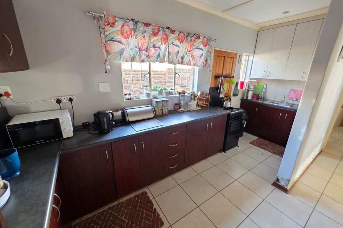 Functional kitchen featuring dark wood-look cabinetry, contrasting countertops, ceramic tiled flooring, and a freestanding stove with ample storage space.