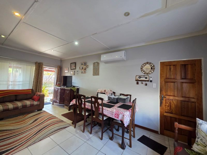 Open-plan living and dining area featuring tiled flooring, recessed lighting, and a split-system air conditioner with access to an outdoor patio.
