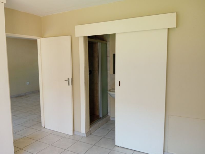 A neutral hallway area featuring tiled flooring and a sliding door providing access to an adjacent bathroom space.