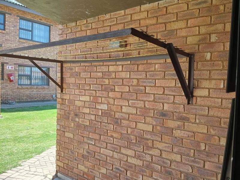 Exterior rear view of the apartment featuring a brick facade and a wall-mounted metal clothes drying rack.