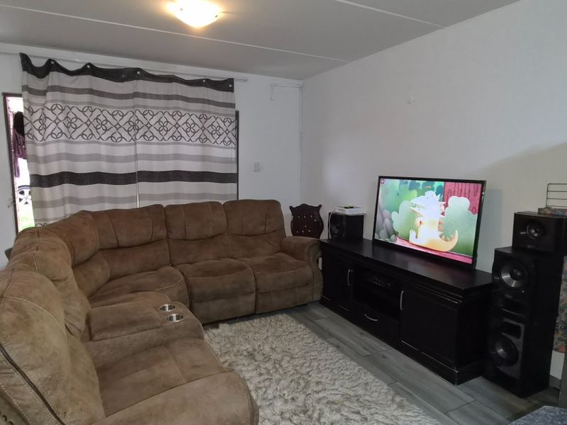 A functional living room featuring laminate flooring and neutral wall finishes, providing a comfortable space for relaxation.