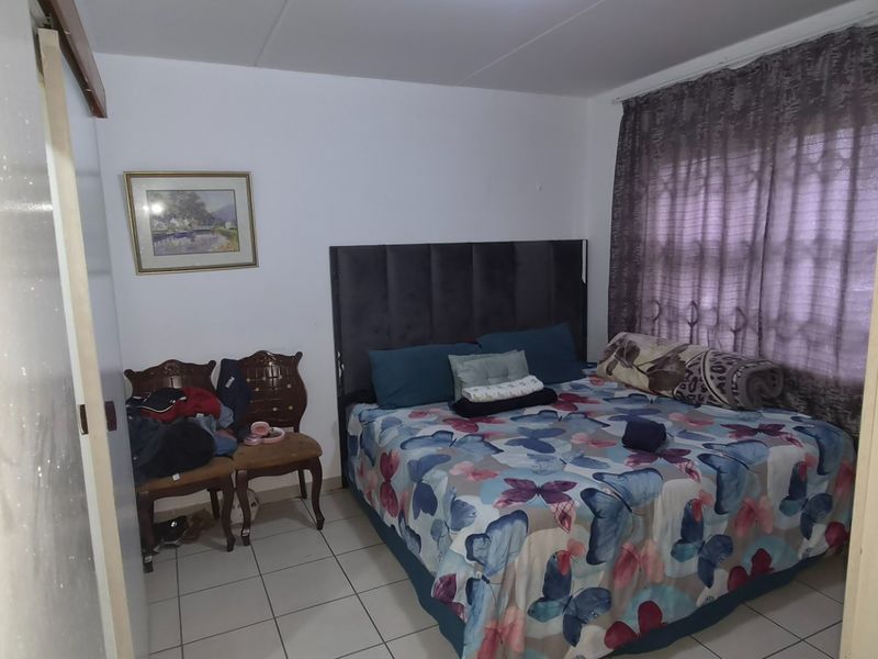 A standard bedroom featuring tiled flooring and a built-in cupboard, providing a functional sleeping space.