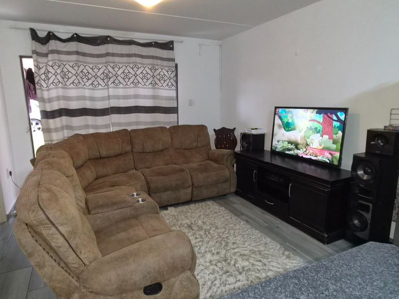A functional living room featuring tiled flooring and a sliding door providing access to the exterior.