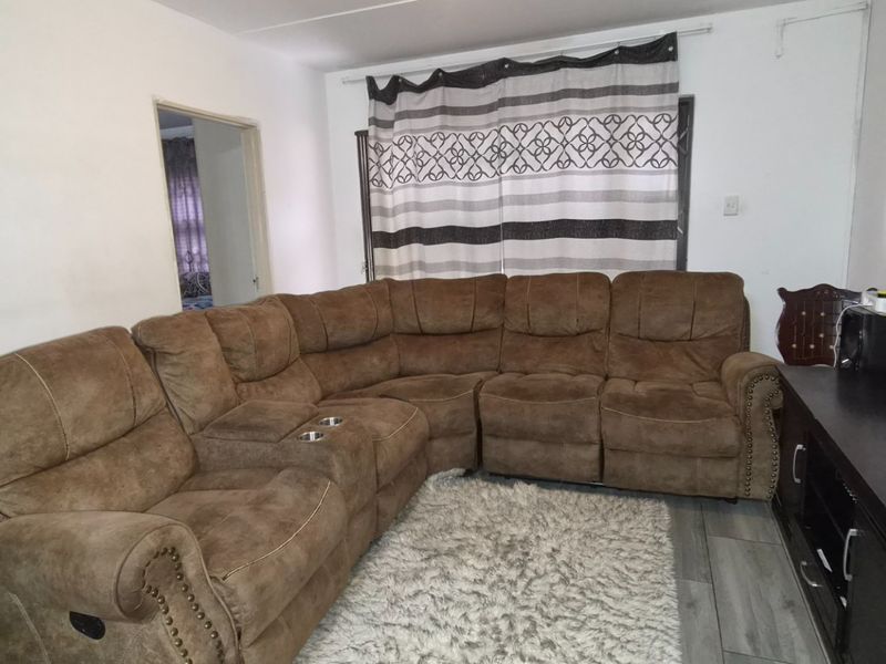 A living room featuring laminate flooring and neutral wall finishes, providing a functional space for relaxation.