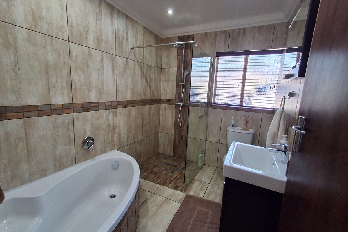 Modern bathroom featuring a freestanding bathtub, a spacious walk-in shower with glass screen, vanity basin, and neutral floor-to-ceiling tiling.