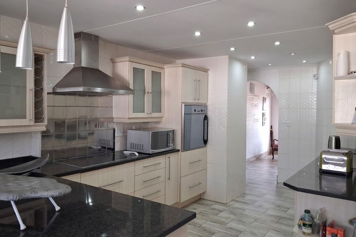 A well-maintained kitchen featuring light-toned cabinetry, dark granite countertops, integrated stainless steel appliances, and modern recessed lighting with tiled finishes throughout.