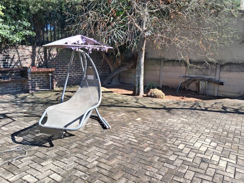 Rear garden area featuring brick paving, a built-in brick braai, and perimeter boundary walls.