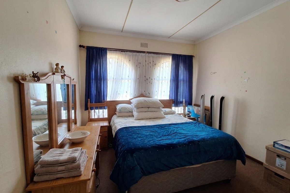 A bedroom featuring carpet flooring, distinctive arch-top windows, and a ceiling rose, requiring cosmetic updates to improve its overall condition.