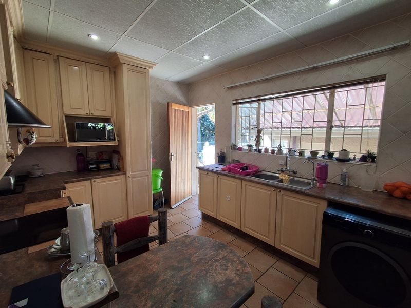 A functional kitchen featuring built-in cabinetry, laminate countertops, a double basin sink, and tiled flooring with direct access to the exterior.