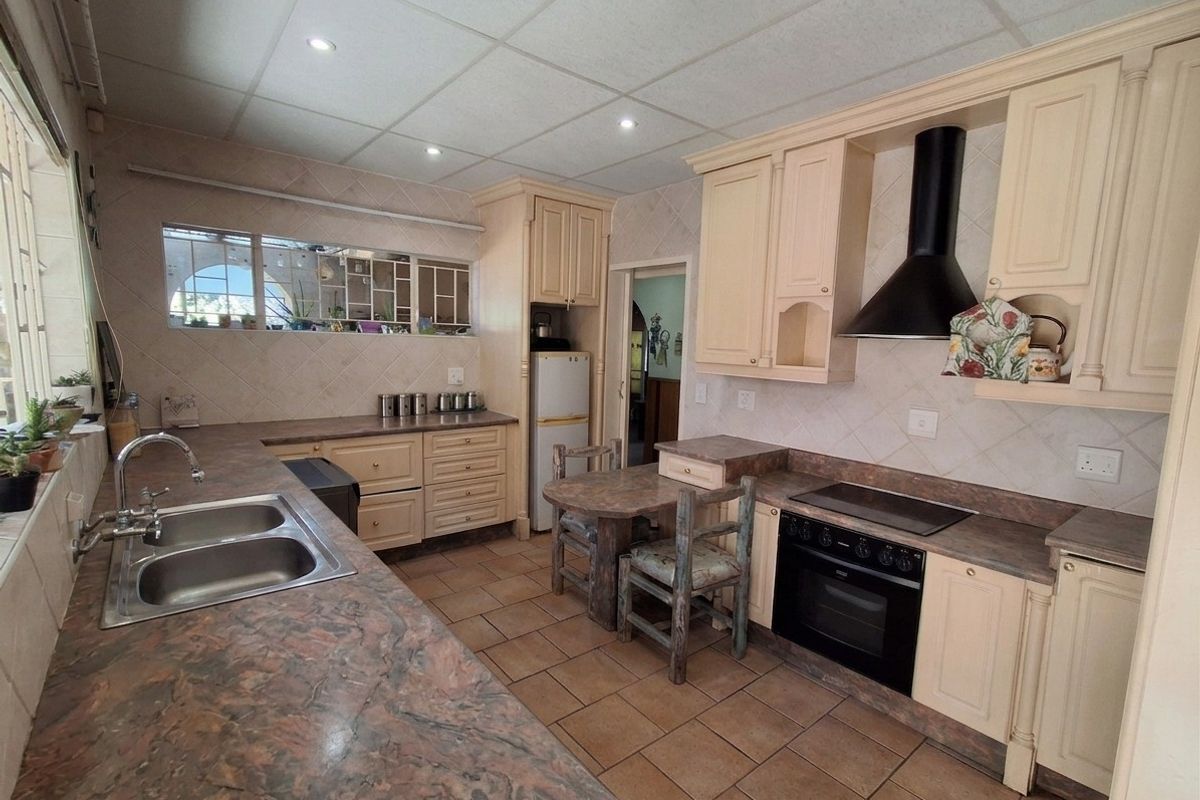Functional kitchen featuring built-in cabinetry, electric oven, hob with extractor fan, double basin sink, and tiled flooring with a neutral backsplash.