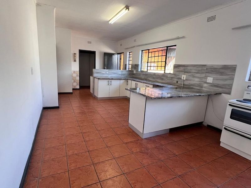 Spacious kitchen featuring built-in cabinetry, laminate countertops, tiled backsplash, and a freestanding stove, offering a functional layout ready for modern updates.