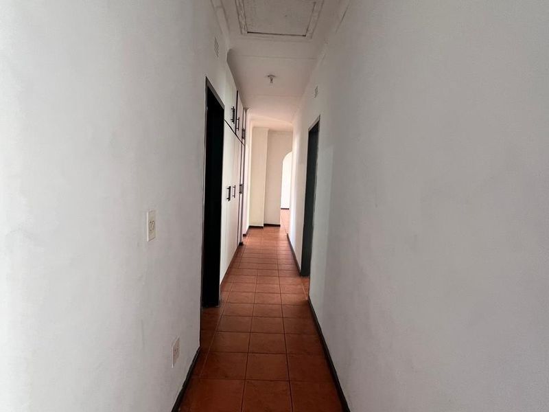A functional hallway featuring tiled flooring and built-in storage cupboards, providing access to various rooms within the home.