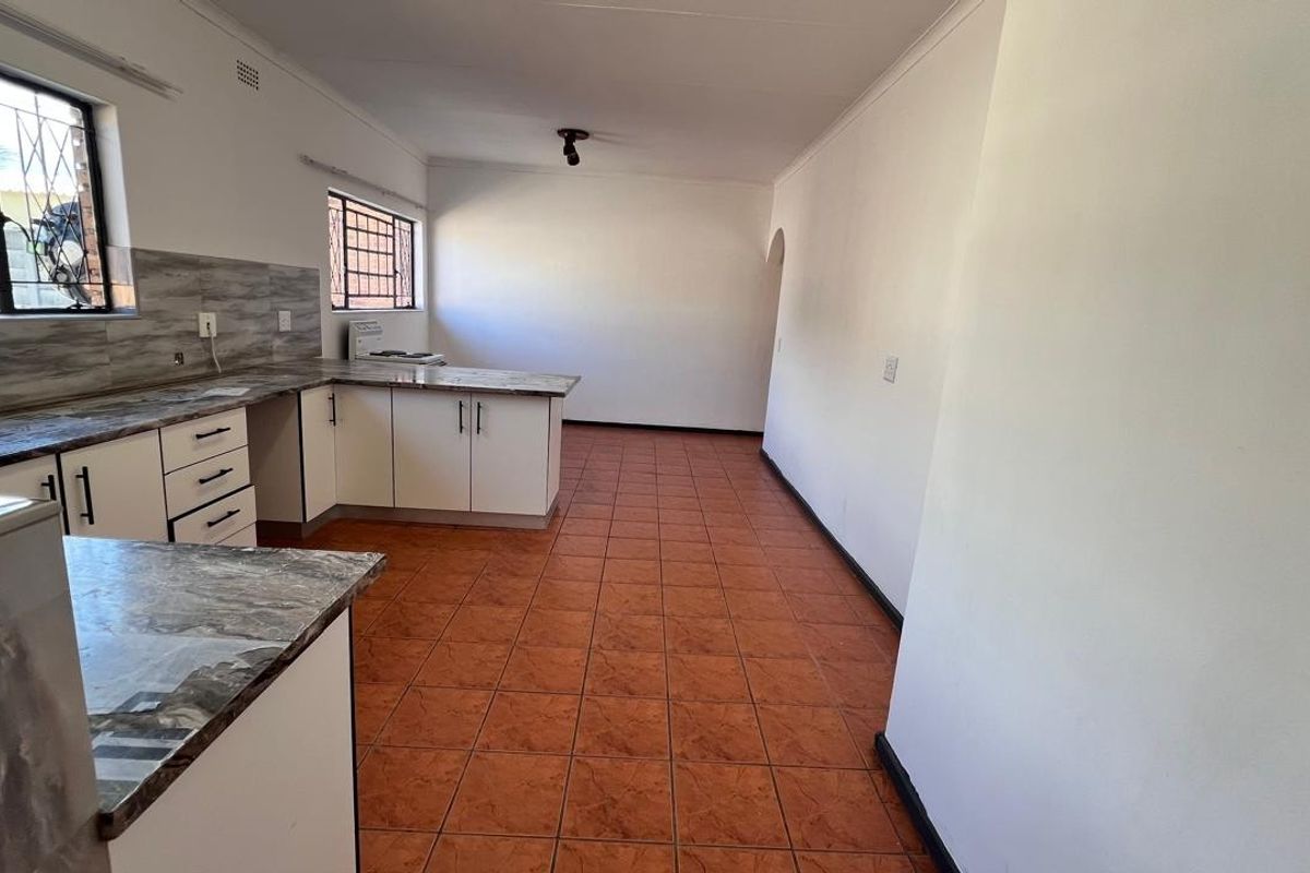 A functional, empty kitchen featuring white cabinetry, laminate countertops, and tiled flooring, offering a blank canvas for potential updates.