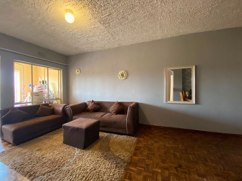 A living room featuring classic parquet flooring and a textured ceiling, offering a neutral base for potential interior updates.