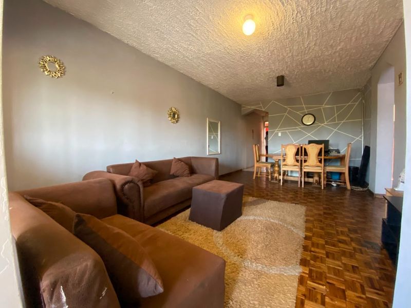 Open plan living and dining area featuring traditional parquet flooring and a textured ceiling, offering a functional layout for daily living.