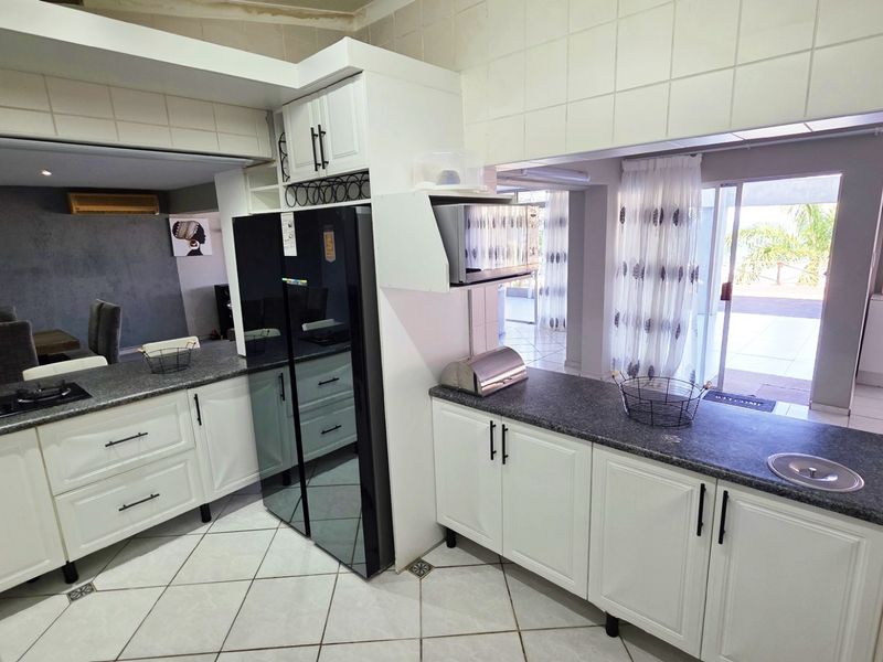 A functional kitchen featuring white cabinetry, granite countertops, a gas hob, and direct access to the outdoor patio area.