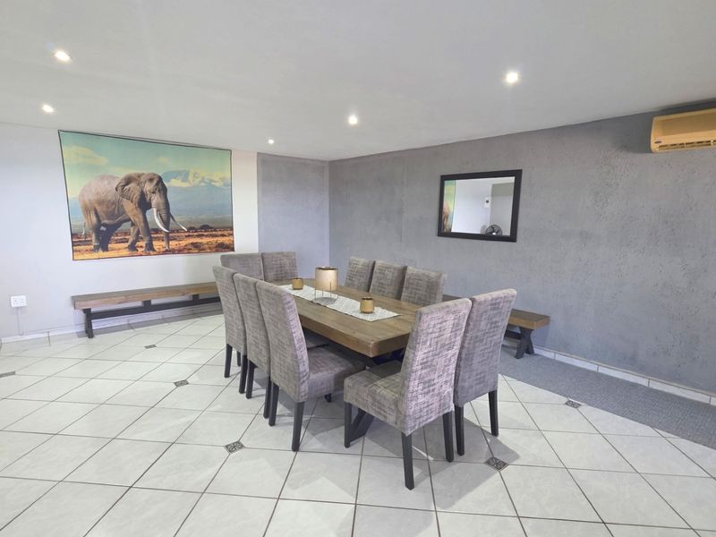 Spacious dining area featuring tiled flooring, recessed downlighting, and a wall-mounted air conditioning unit, providing a functional space for family meals.