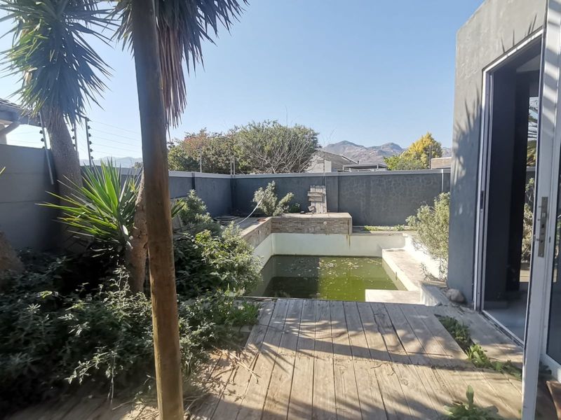 Outdoor pool area featuring a swimming pool with timber decking, enclosed by a perimeter wall with electric fencing.